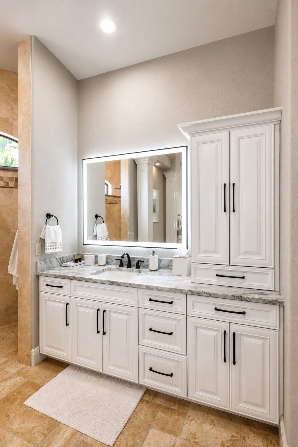 Bathroom vanity after cabinet painting — white cabinets with black hardware, linen tower, and backlit LED mirror