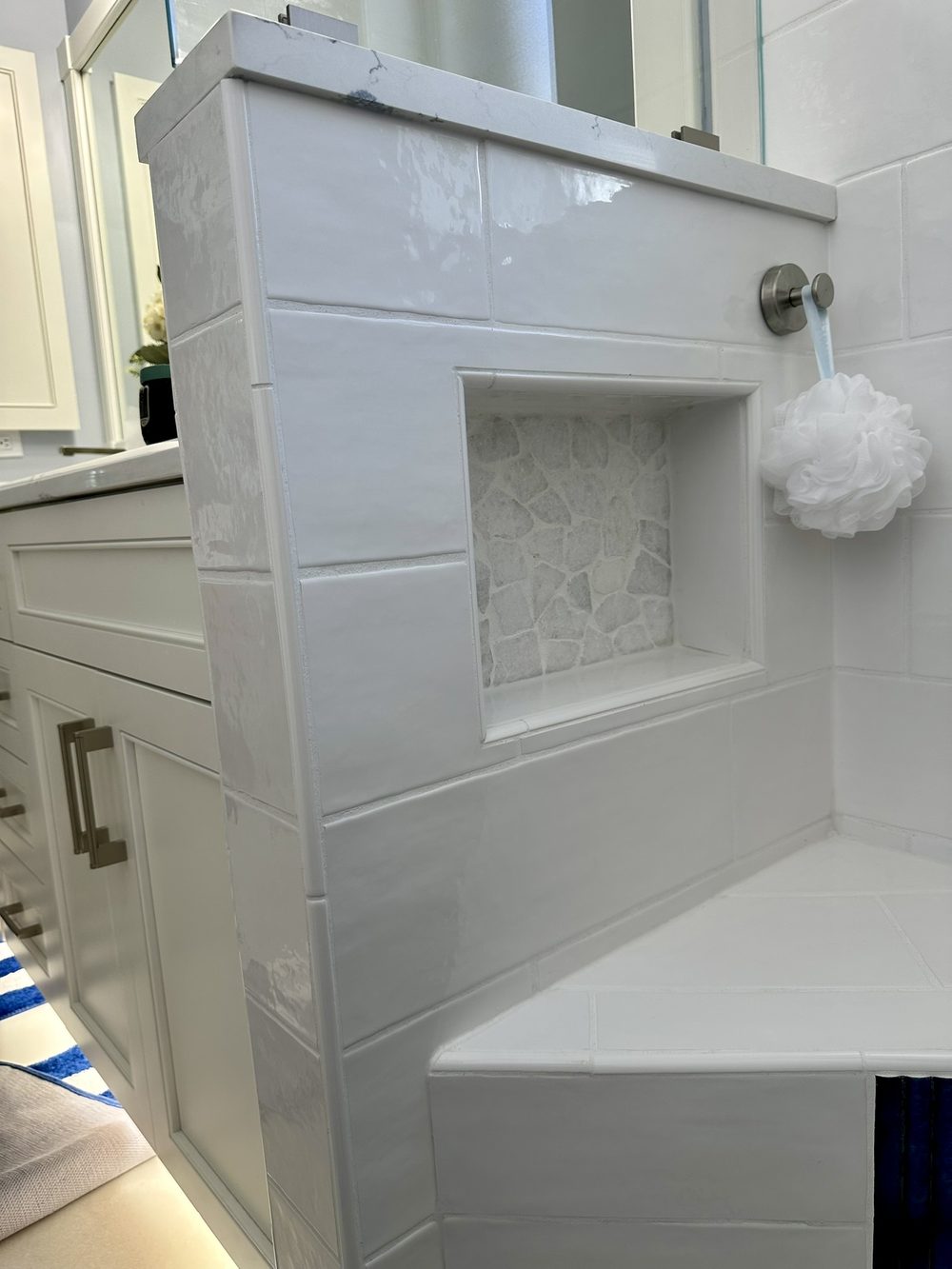 Bathroom after remodel — glossy white subway tile shower with built-in niche and bench