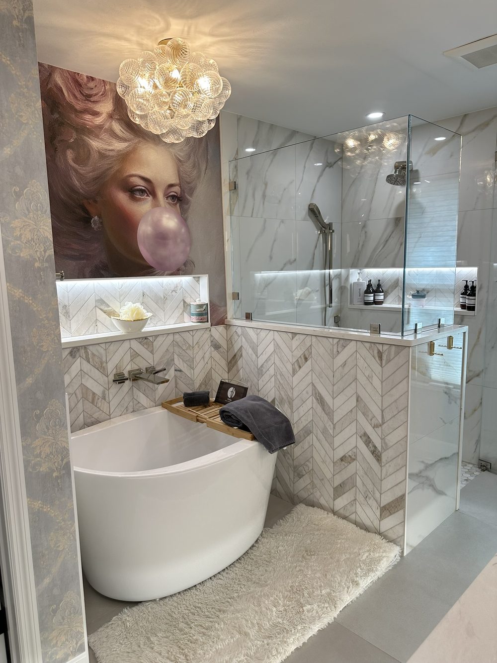 Bathroom after remodel — freestanding tub, chevron marble tile, and glass shower enclosure