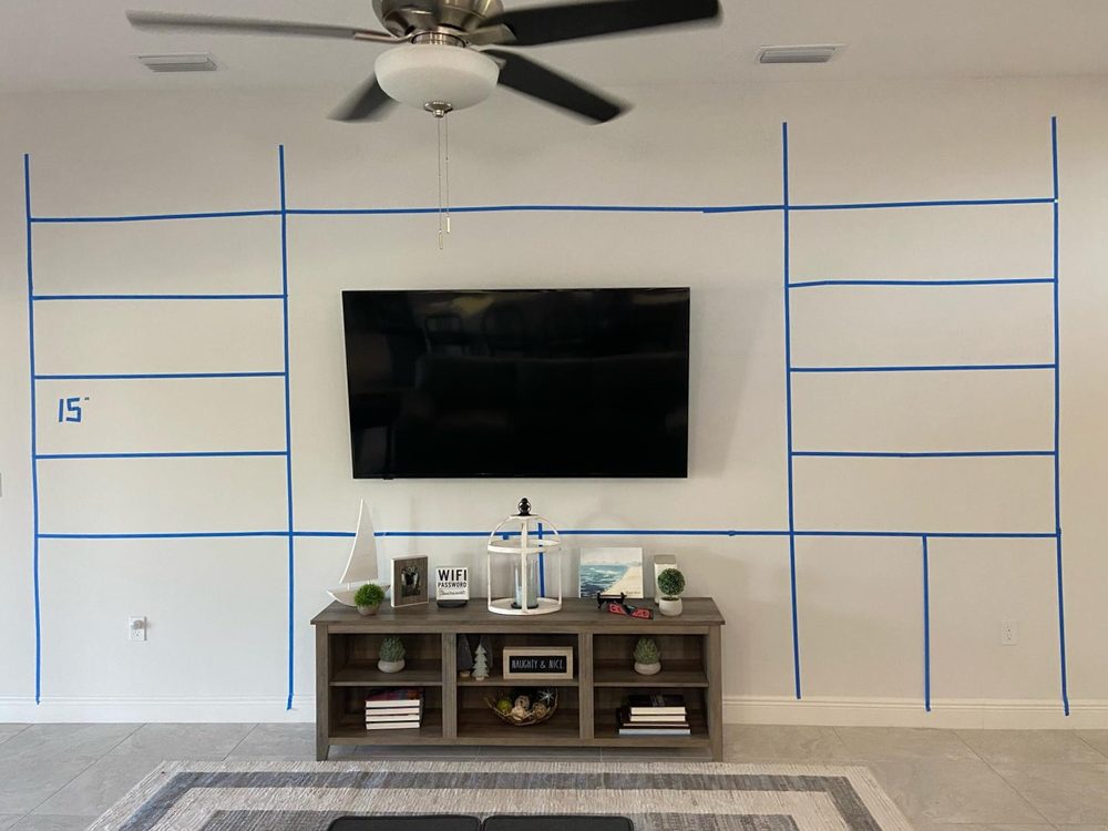 Wall before entertainment center — blue tape layout marking out the built-in cabinetry design