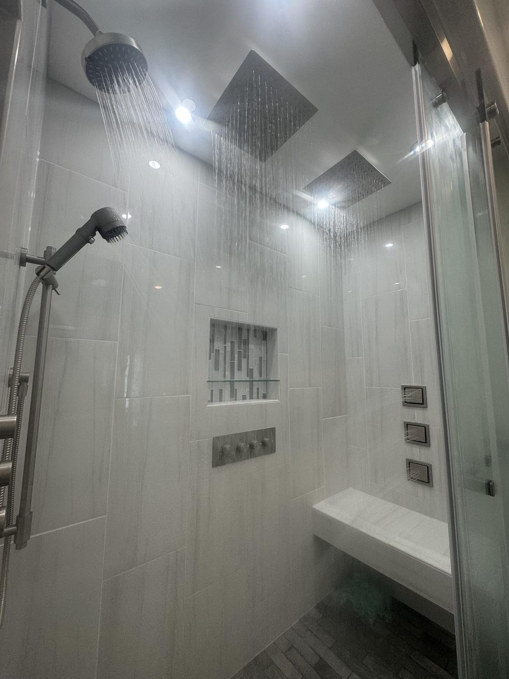 Master bathroom after remodel — luxury steam shower with dual rain heads and marble bench