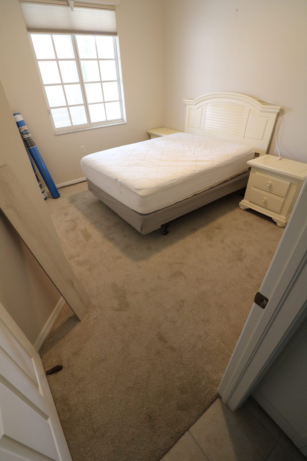 Bedroom before flooring — worn stained beige carpet
